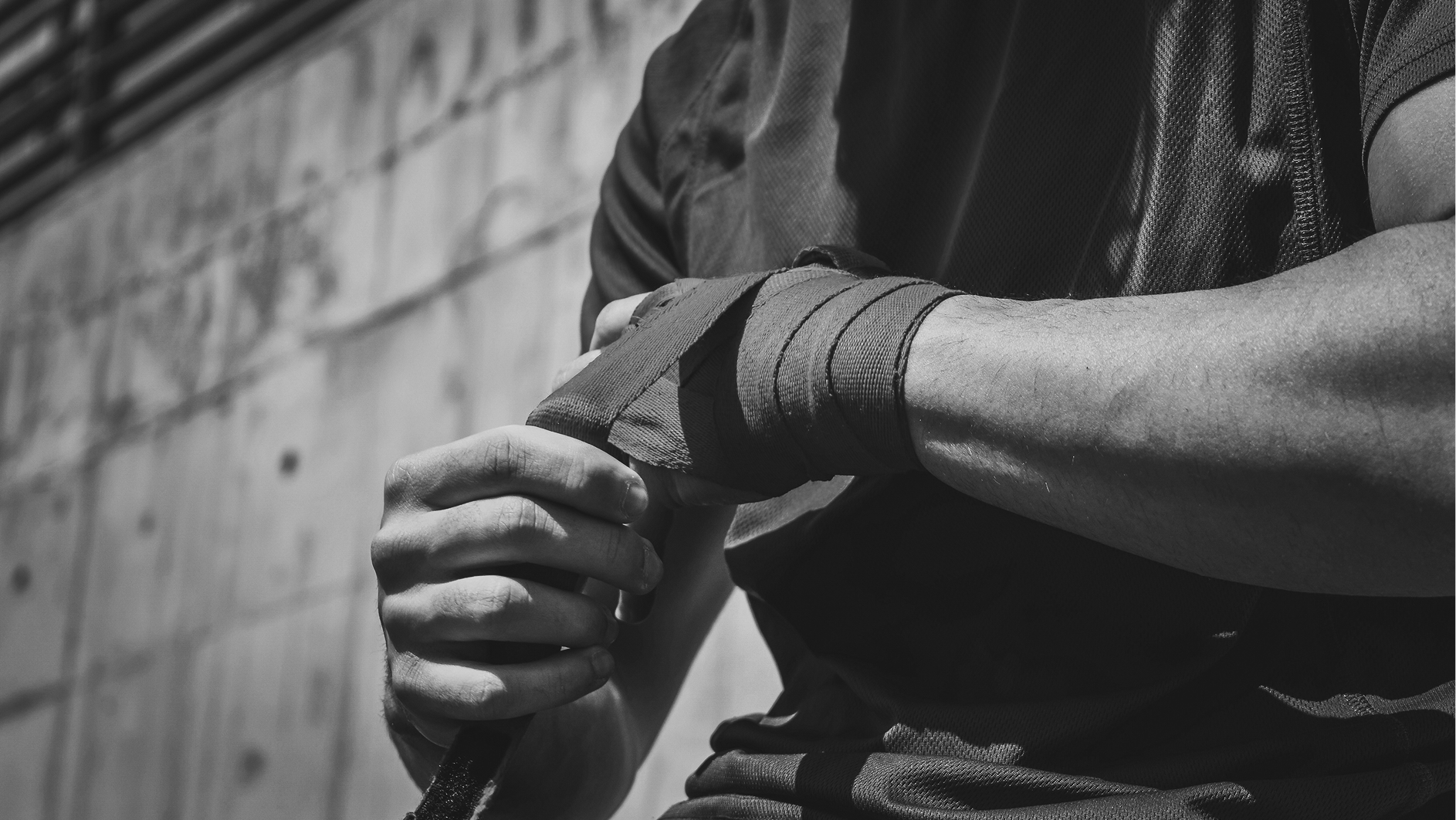 Man wrapping his knuckles in fabric tape preparing for a fight